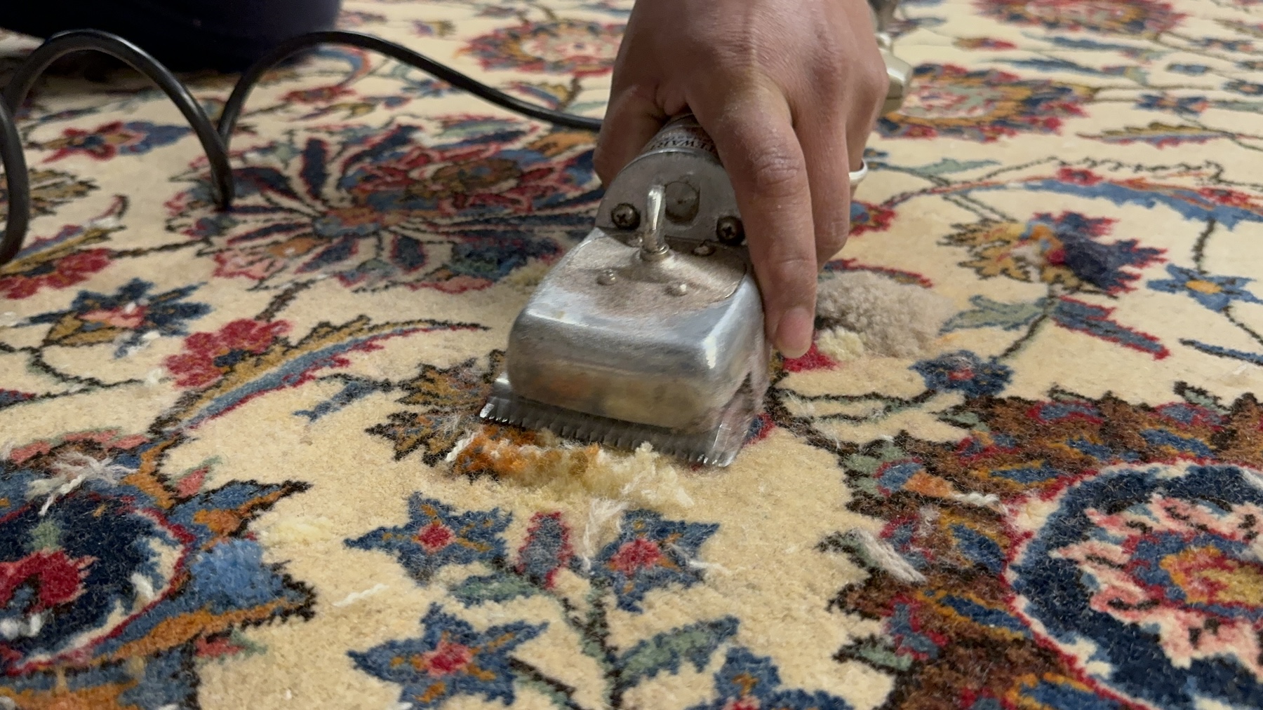 Technician performing a detailed restoration process on a rug, removing damaged fibers and pilling to enhance its appearance and texture.