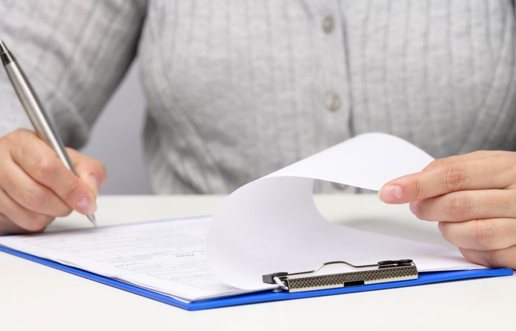 An expert inspecting a vibrant rug on a table, focused on its details and craftsmanship in a bright, organized space